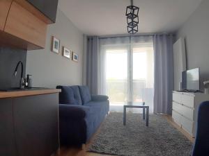 a living room with a blue couch and a tv at Apartament Wawa in Warsaw