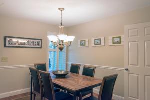a dining room table with chairs and a chandelier at 1135 Summerwind Cottage in Seabrook Island