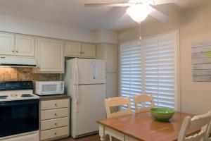 a kitchen with a table and a white refrigerator at 1135 Summerwind Cottage in Seabrook Island