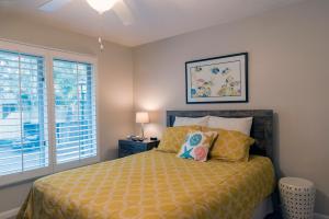 a bedroom with a bed with yellow sheets and a window at 1135 Summerwind Cottage in Seabrook Island