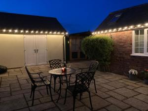 un patio con mesa, sillas y luces en Cream Cottage Annex en Poole