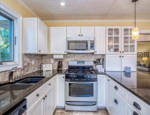 a kitchen with white cabinets and a stove and a sink at 779 Spinnaker Beach House in Seabrook Island