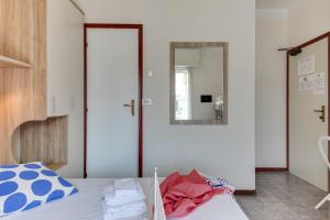 B&B Villa Madana في ريميني: غرفة نوم مع سرير ومرآة على الحائط