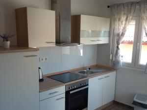 a kitchen with white cabinets and a sink and a window at Frka-Petešić in Sali