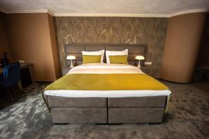1 dormitorio con 1 cama grande con almohadas amarillas en Hotel & Restaurant Infinity, en Lichtmis