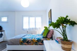 a bedroom with a bed and a table with a plant at Le coquet - Balcon - Proche gare - Parking in Bourg-en-Bresse