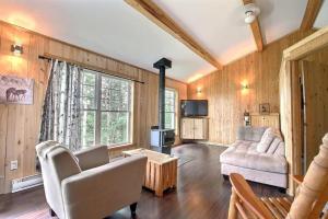 a living room with a couch and a tv at Le Chouette Chalet in La Malbaie