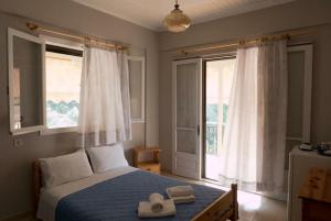 a bedroom with a bed with two hats and two windows at CHRISTINAS STUDIOS NIKIANA in Nikiana