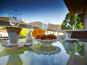 a glass table with wine glasses and a bowl of food at Hotel Methanion in Methana