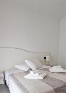 1 dormitorio con 2 camas, sábanas blancas y toallas en Residenza XX Settembre, en Maslianico