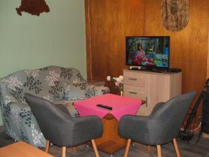 ein Wohnzimmer mit einem Sofa, einem Tisch und einem TV in der Unterkunft Zsiga Apartmanház in Balatonszabadi