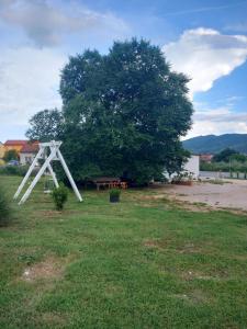 a white structure sitting in a field next to a tree at Apartments Kruno in Međugorje