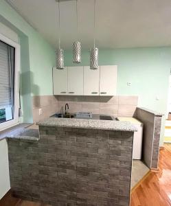 cocina con armarios blancos y encimera de ladrillo en Stan na dan Milena, en Trebinje