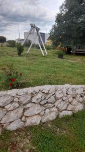 una escultura en un campo junto a una pared de piedra en Apartments Kruno, en Međugorje