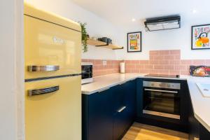 a kitchen with blue cabinets and a yellow refrigerator at Cosy Blue Shells Cottage - 2bedrooms - Garden - 5mins beach - 1min Shell Grotto in Margate