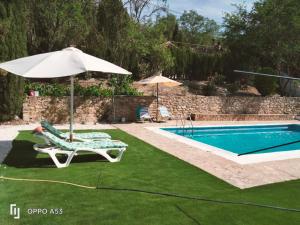 a chair and an umbrella next to a swimming pool at Casa el Tío Enrique in Cazorla