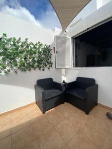 two chairs and a window with a plant on a wall at HAPPY HOUSE NANE in Playa Honda