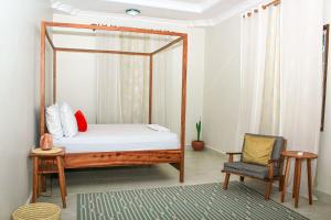 a bedroom with a canopy bed and a chair at Kwale Residence in Kiembi Samaki