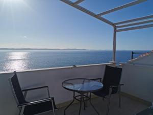 una mesa y sillas en un balcón con vistas al océano en Villa Katarina en Petrcane