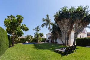 a yard with a bench and palm trees and a house at Casa Azahar y Casa Buganvilla in Gandía