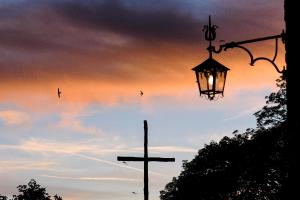 a cross and a street light with birds flying in the sky at Casa PerFerie “PASTOR ANGELICUS” in La Verna