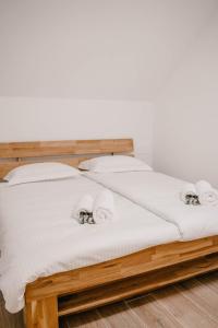 uma cama de madeira com lençóis brancos e almofadas em Chalet HerMes arT em Idrija