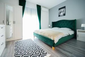 a bedroom with a green bed and a rug at GreenForest Apartament Baile Felix in Baile Felix