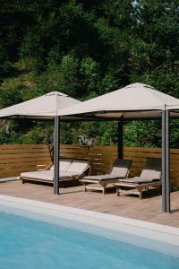 2 sillas y sombrillas junto a una piscina en Chalet HerMes arT, en Idrija