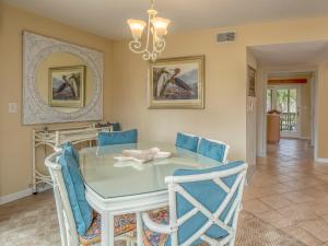 a dining room with a glass table and blue chairs at 724 Spinnaker Beach Villa in Seabrook Island
