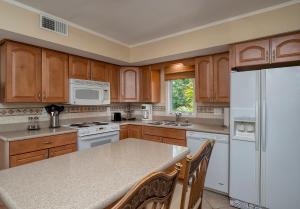 a kitchen with wooden cabinets and a white refrigerator at 724 Spinnaker Beach Villa in Seabrook Island +25 photos