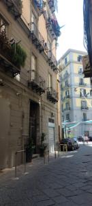 una strada cittadina con edifici e una macchina parcheggiata di fronte di Casa Cosmedin a Napoli