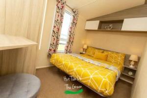 a bedroom with a yellow bed and a window at Home from Home Lettings at Tattershall Lakes - The Green in Tattershall