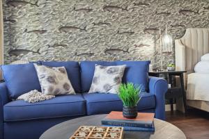5mins to DT Petoskey Lakefront 50 inches 4K TV في بتوسكي: أريكة زرقاء في غرفة معيشة مع جدار حجري