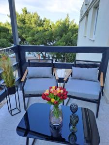 een balkon met twee banken en een tafel met een vaas met bloemen bij Bella Luxury Apartment in Sali