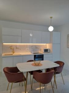 - une cuisine blanche avec une table et des chaises dans l'établissement Bella Luxury Apartment, à Sali