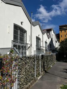 a white building with a stone wall and a fence at YR Apartments Milan - Bocconi in Milan