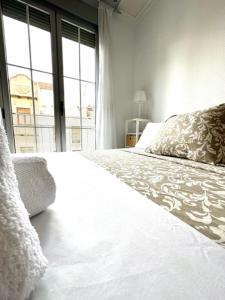 a white bed in a room with a large window at Apartamento Claudio Marcelo, 1 in Córdoba