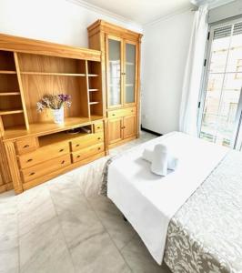 a bedroom with a white bed and a wooden cabinet at Apartamento Claudio Marcelo, 1 in Córdoba