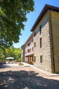 a large brick building with a tree next to it at Casa PerFerie “PASTOR ANGELICUS” in La Verna