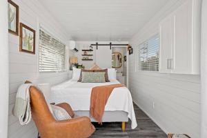 a white bedroom with a bed and a chair at New The Saguaro-Tiny Shipping Container Home in Fredericksburg