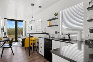 uma cozinha com um lavatório e uma mesa com cadeiras em New The Yellow Beacon-Luxury Shipping Container em Fredericksburg