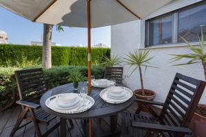 a wooden table with chairs and an umbrella at Casa Azahar y Casa Buganvilla in Gandía