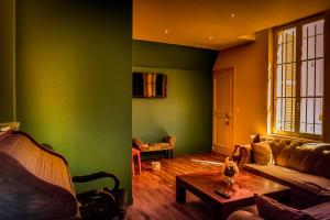 a living room with green walls and a couch and a table at Demeure D'Argonne in Sainte-Menehould