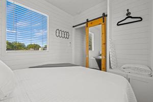 a white bedroom with a bed and a window at New! The Texas Longhorn-Luxury Container Home in Fredericksburg