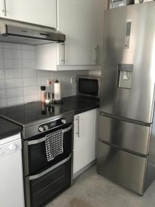 a kitchen with a stainless steel refrigerator and white cabinets at Comfortable rooms with live in host, walking distance to the High St & more in Glastonbury