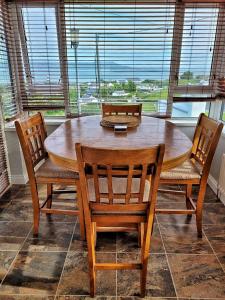 a wooden table with four chairs and a large window at Lighthouse Farm in Greencastle