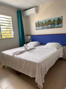 圣吕斯Hôtel DOUCE VAGUE的一间卧室设有两张带白色床单的床和窗户。