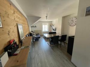 a living room with a dining table and a clock on the wall at Charmant F3 à Gérardmer Centre in Gérardmer