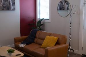 Sofá marrón en la sala de estar con espejo en New Spacious Studio Suite with Mountain Views en Kamloops