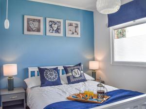 a blue bedroom with a bed with a tray of food on it at Hectors House in Scratby